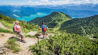 Wanderer auf Berg vor See, Aussicht auf das Zweiseenland, Kochel a. See und Walchensee, Tourist Information Kochel a. See
