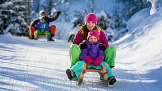 Mutter mit Kind auf Schlitten, Rodelbahn, Familie auf Rodelbahn, Schlittenfahren, Salzburger Sportwelt, 