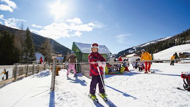 Kinder auf Skiern vor Bergkulisse, Kirchleitn Familien Feriendorf