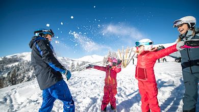 Familie macht Schneeballschlacht, Familie im Schnee, Eltern mit Kindern vor Bergkulisse im Schnee, Schneevergnügen für Familien, Winterurlaub, Salzburger Sportwelt, 