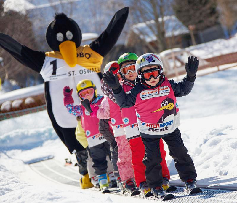 Kinder auf Skiern und ein Mensch im Pinguin-Kostüm, Kirchleitn Familien Feriendorf